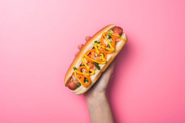 Przycięty widok kobiety trzymającej pyszne hot dogi na różowo