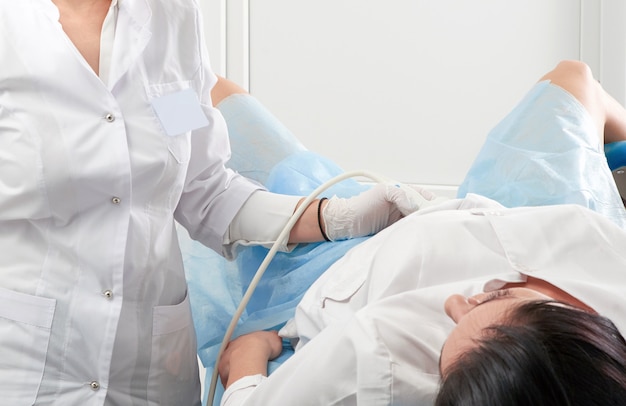 Przycięty widok kobiety w ciąży przechodzącej badanie ultrasonograficzne w biurze ginekologa
