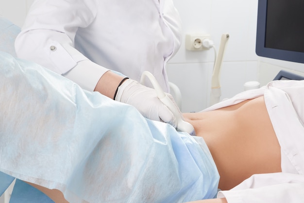 Przycięty widok kobiety w gabinecie ginekologa wykonującym badanie ultrasonograficzne dolnej części brzucha