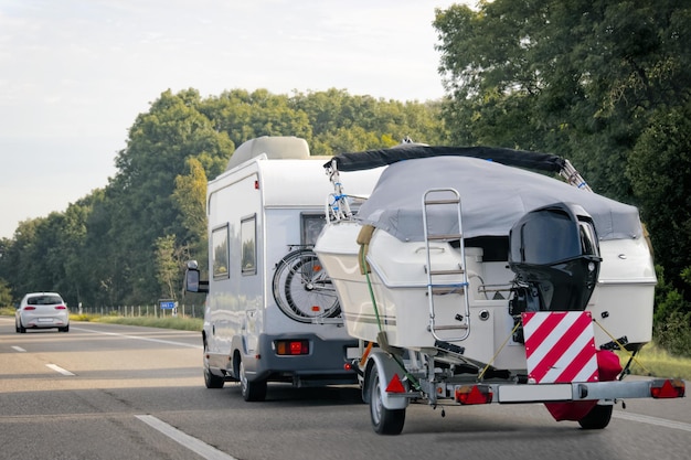 Zdjęcie przyczepa kempingowa z przyczepą do łodzi motorowych na drodze w szwajcarii.