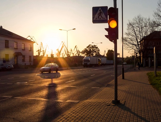 Przydrożne latarnie i dźwigi portowe na tle zachodzącego słońca w Kłajpedzie na Litwie