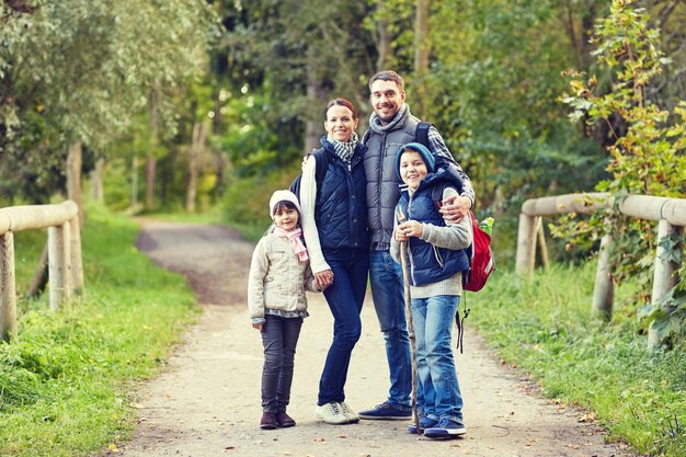 Przygoda, podróże, turystyka, wędrówki i ludzie koncepcja - szczęśliwa rodzina spacerując z plecakami w lesie