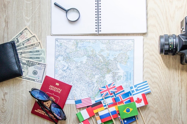 Przygotowanie do podróży paszport pieniądze mapa drogowa okulary przeciwsłoneczneszkło powiększające retro aparat fotograficzny notatnik na drewnianym stole