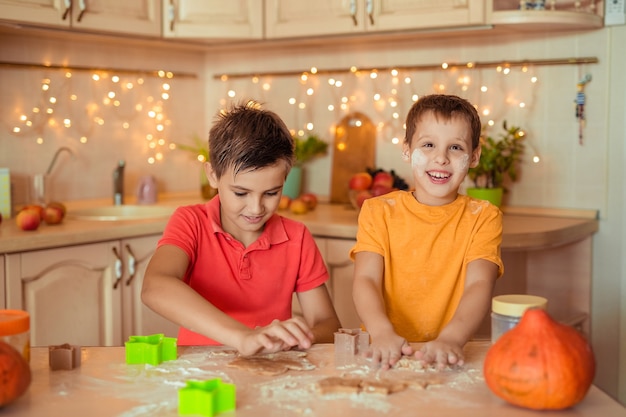 przygotowanie do świątecznego halloween. dwoje wesołych dzieci robi ciasteczka w kuchni
