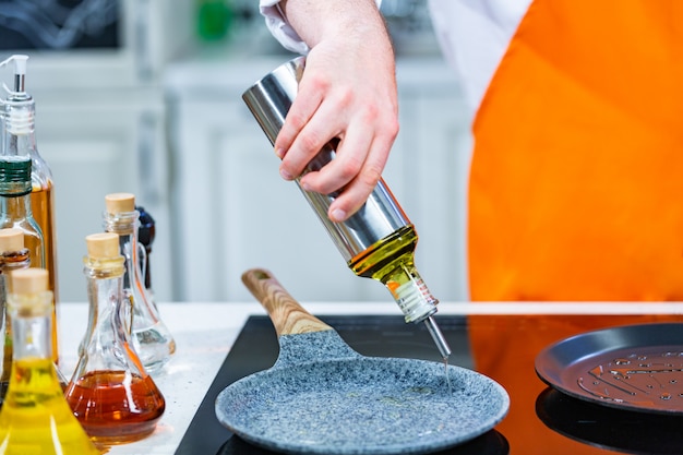 Przygotowanie kuchni: szef kuchni wlać olej na patelnię