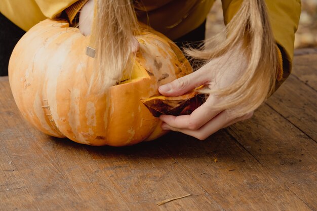 Przygotowanie na Halloween: dziewczyna wyciąga pestki dyni. Zbliżenie. Koncepcja dekoracji wakacje. Kobieta przygotowuje jack-o-latarnia. Impreza dekoracyjna. Mały pomocnik.