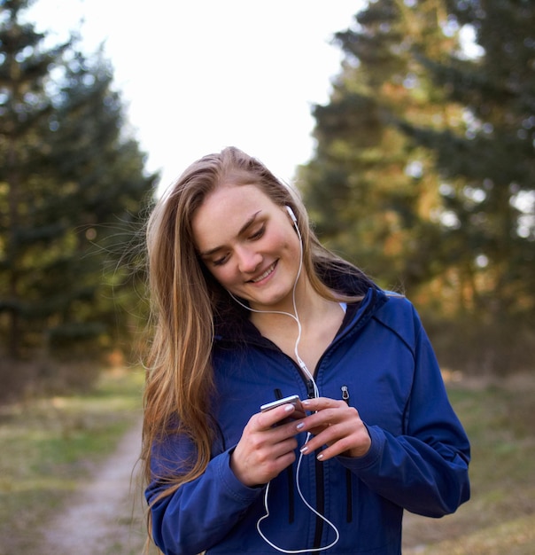 Przygotowuję muzykę do biegania Ujęcie atrakcyjnej i wysportowanej młodej kobiety przygotowującej swoją playlistę przed biegiem