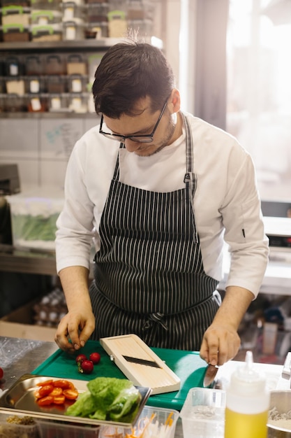 Przygotowywanie warzyw na pyszne danie z miski męskiego szefa kuchni we współczesnej kuchni restauracyjnej