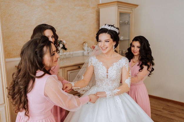 Przyjaciel pomaga panny młodej zawiązać sukienkę kobieta pomaga przyjaciółce zawiązać guziki na tyłach sukni ślubnej poranek panny młodzej tworzenie rodziny ważne wydarzenie