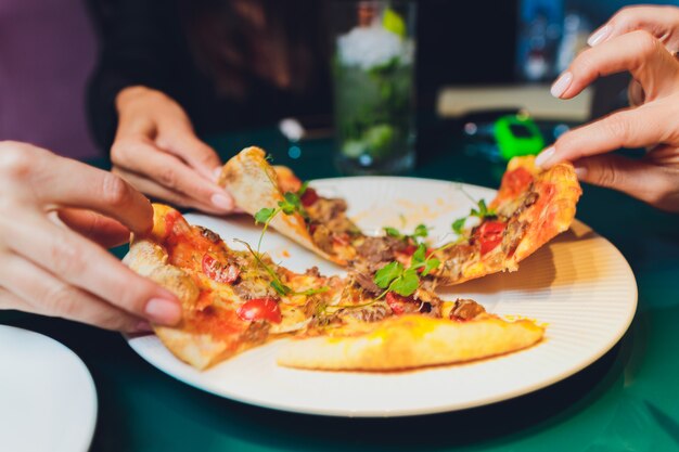 Przyjaciele Bierze Plasterki Smakowita Pizza Od Talerza, Zamykają W Górę Widoku.