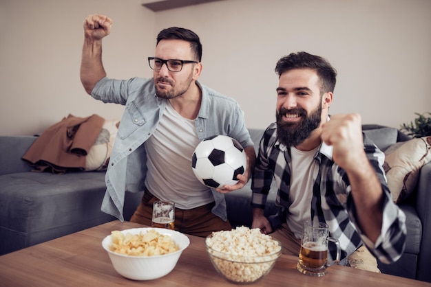 Przyjaciele cieszący się piłką nożną w telewizji