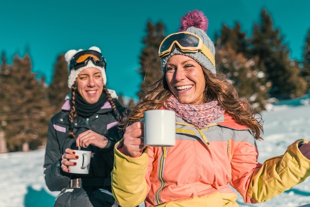 Przyjaciele cieszący się zimowym dniem na górze, pijący kawę lub herbatę na świeżym powietrzu