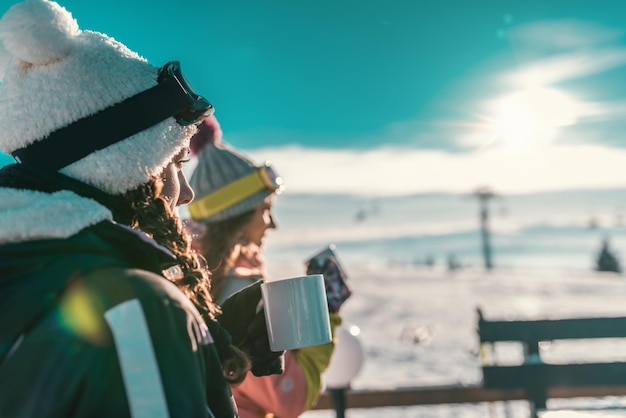 Przyjaciele cieszący się zimowym dniem na górze, pijący kawę lub herbatę na świeżym powietrzu