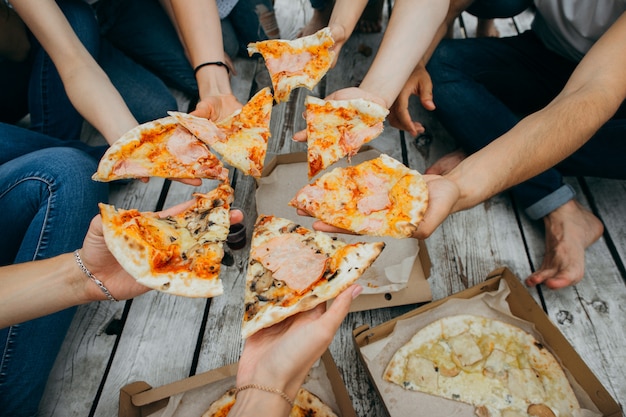 Zdjęcie przyjaciele je pizzę na drewnianym molo