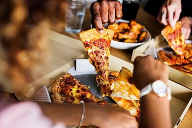 Zdjęcie przyjaciele jedzą razem pizzę w domu.