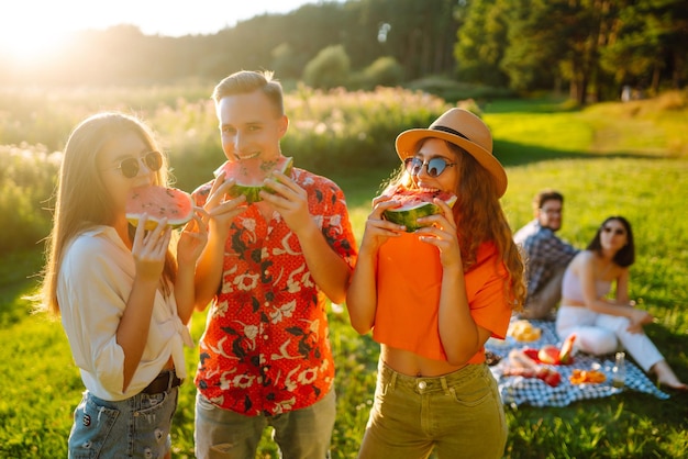 Zdjęcie przyjaciele jedzenia arbuza na piknik ludzie korzystają z czasu letniego ludzie podróżują wakacje koncepcji
