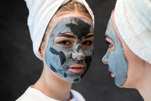 Przyjaciele, kobiety robią z błota i gliny maskę jako środek przeciwstarzeniowy izolowany na czarnym Spa wellness Stay beautiful healthcare grooming