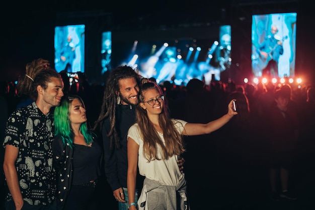 Przyjaciele na letnim festiwalu muzycznym robiący selfie smartfonem