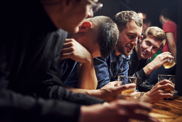 Przyjaciele odpoczywają w pubie z alkoholem w rękach