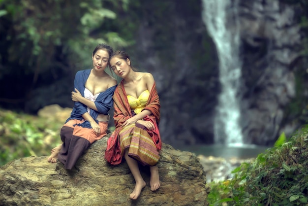 Zdjęcie przyjaciele odpoczywający na skale przy wodospadzie w lesie