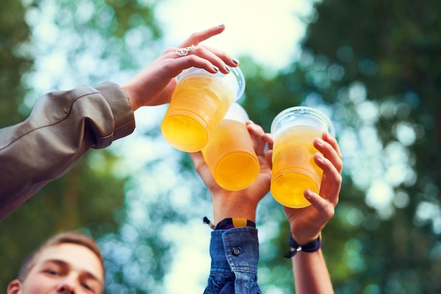 Przyjaciele piwo i toasting w przyrodzie na świętowanie więź i jedność w Kanadzie z niskiego kąta Grupa ludzi ręce i kubki z alkoholem dla zabawy rozrywki i przyjemności na świeżym powietrzu w lesie