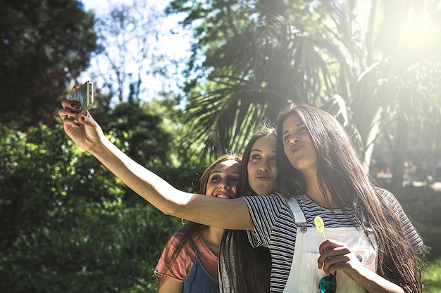 Zdjęcie przyjaciele robią sobie selfie przez telefon komórkowy na drzewach.