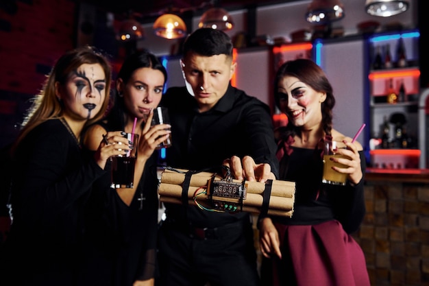 Przyjaciele są na tematycznym przyjęciu halloweenowym w przerażającym makijażu i kostiumach oraz bombie w dłoniach.