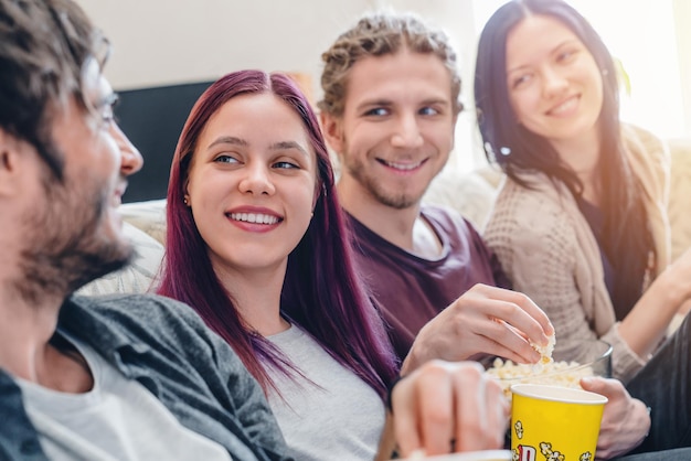 Przyjaciele Siedzący Na Kanapie Bawią Się I Jedzą Popcorn Podczas Oglądania Filmu W Domu