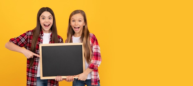 Zdjęcie przyjaciele uczennic zadziwili nastolatki w kraciastym palcu wskazującym na szkolnej tablicy do kopiowania