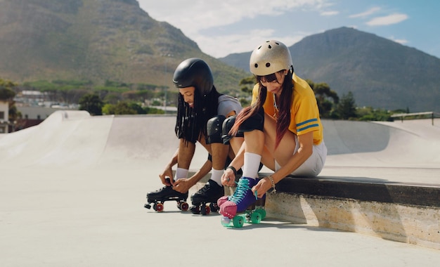 Przyjaciele w skateparku miejskim i jeżdżący na rolkach ze sportową zabawą na świeżym powietrzu i gotowi do jazdy na łyżwach w mieście z kaskiem dla bezpieczeństwa Młody murzyn i kobieta uprawiają sporty ekstremalne i styl życia