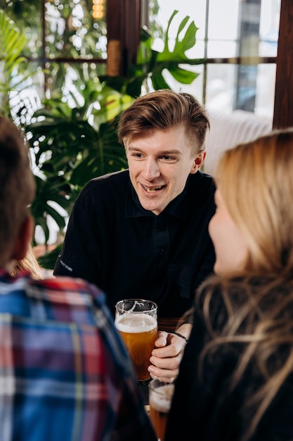 Zdjęcie przyjaciele wznoszą toast i bawią się razem, pijąc piwo i koktajle w happy hour w restauracji pubowej koncepcja czasu na imprezę w stylu życia społecznego