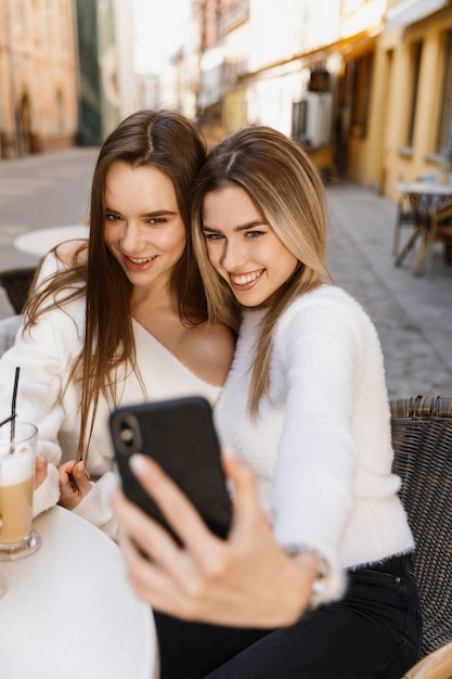 Przyjaciółki przy selfie przy stoliku w kawiarni