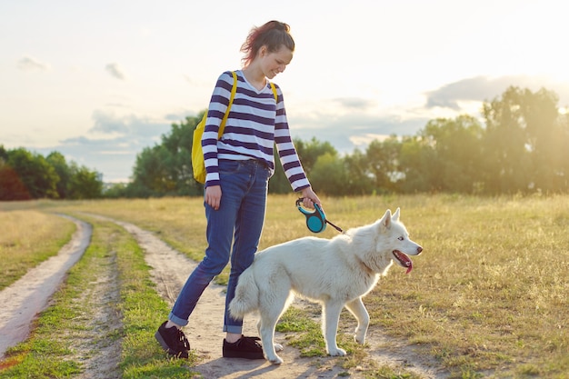 Przyjaźń dziewczyny i psy, nastolatek i zwierzę husky spacerują na świeżym powietrzu, piękny krajobraz natura łąka