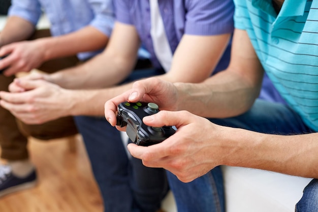 Zdjęcie przyjaźń, technologia, gry i koncepcja domu - zbliżenie męskich przyjaciół grających w gry wideo w domu