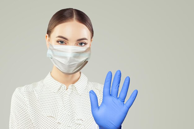 Przyjazna pielęgniarka w masce twarzowej pokazująca gest zatrzymania na białym tle