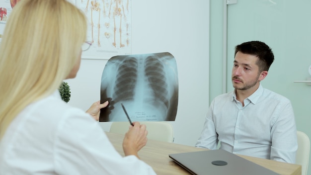 Zdjęcie przyjazny lekarz kobieta daje dobre wieści x-ray płuc pacjenta pacjenta w szpitalu kryty. opieka zdrowotna, koncepcja obsługi personelu medycznego i lekarza.
