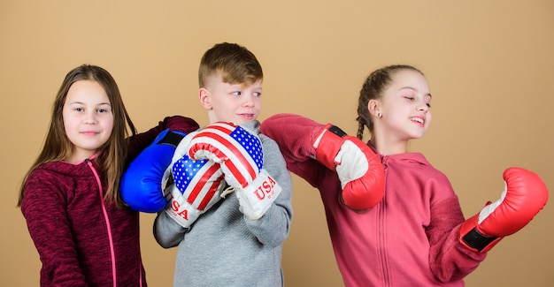 Zdjęcie przyjazny sparing. koncepcja amerykańskiego sportu. dzieci sportowo ćwiczące umiejętności bokserskie. sport bokserski. rozpocznij karierę bokserską. umiejętności samoobrony. chłopcy i dziewczęta noszą rękawice bokserskie z flagą usa.