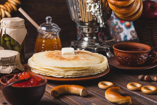 Zdjęcie przyjęcie herbaty z naleśnikami, herbatą samovarową i ogórkami.