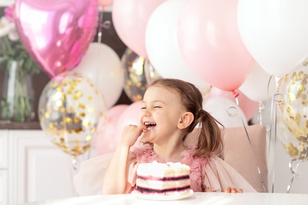 Przyjęcie Urodzinowe Uśmiechnięte Szczęśliwe Dziecko Dziewczynka Siedzi Przy Stole Nad Balonami Jedz Tort Urodzinowy Używaj Ręki