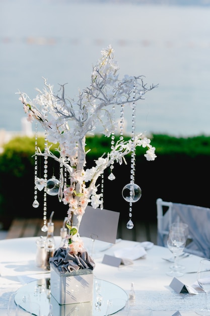 Przyjęcie weselne przy stole weselnym dekoracja stołu weselnego biała gałązka z drzewa wisiorki kryształowe