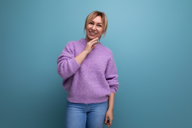 Przyjemna blond młoda konsultantka w fioletowej bluzie z kapturem uśmiechająca się na niebieskim tle z miejsca na kopię