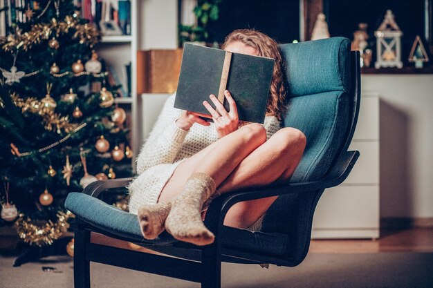 Przyjemny czas Bożego Narodzenia w domu kobieta czyta książkę hygge