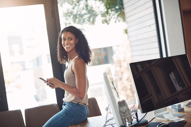 Przypadkowa kobieta trzymająca telefon w domowym biurze, ciesząca się pracą zdalnie siedząc na biurku Szczery, prawdziwy i autentyczny moment pracownika marketingu cyfrowego Uśmiechnięta kobieta robi sobie przerwę w mediach społecznościowych