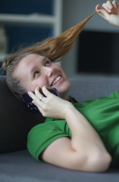 Zdjęcie przypadkowa młoda zdumiona kobieta w rozmowie telefonicznej flirtuje przez telefon, rozmawiając, skręcając włosy