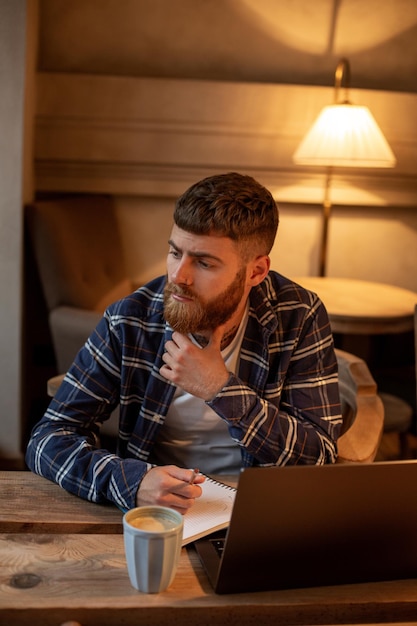 Przypadkowy biznesmen lub freelancer planujący swoją pracę na notebooku pracujący na laptopie z inteligentnym...