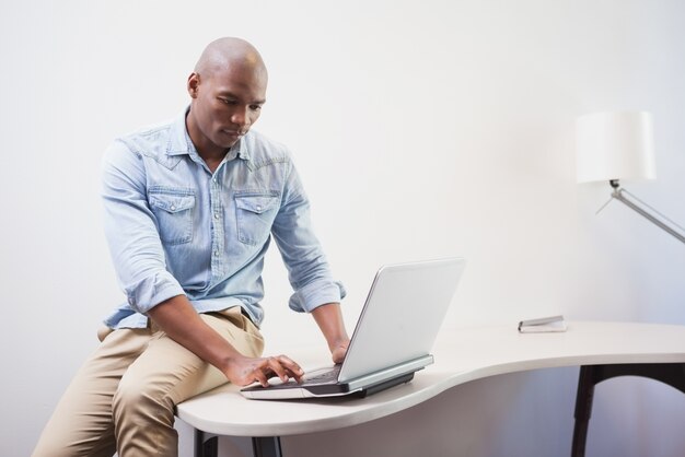 Przypadkowy biznesmen używa jego laptop przy biurkiem