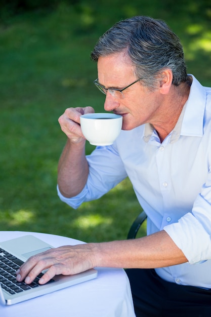 Przypadkowy biznesmen używa laptop i mieć kawę