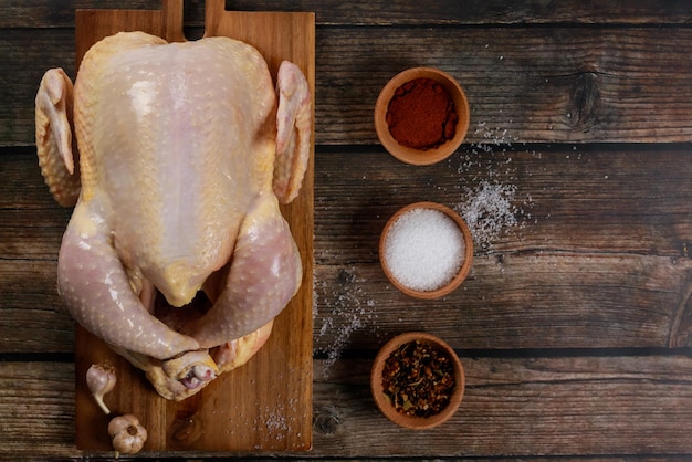 Przyprawy do gotowania towarzyszą surowemu kurczakowi na desce do cięcia