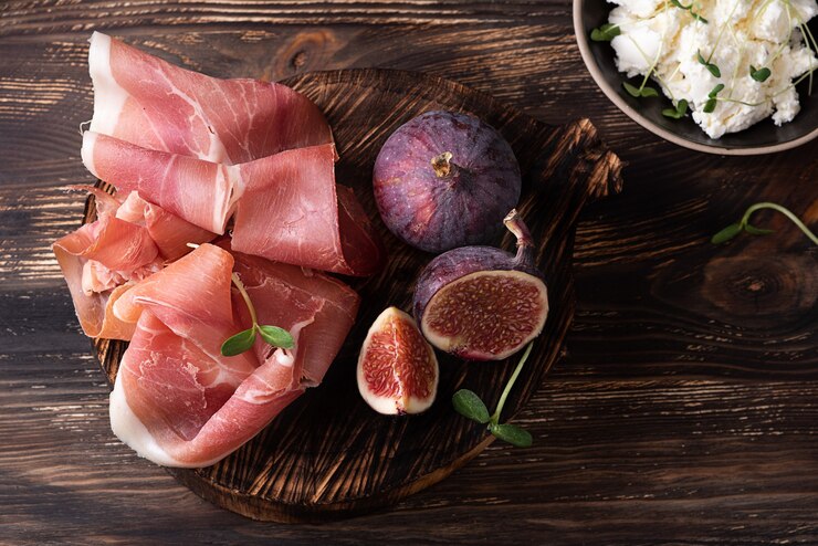Zdjęcie przystawka z szynki suszonej na sucho, plastry prosciutto z figami na ciemnym drewnianym tle, styl rustykalny.