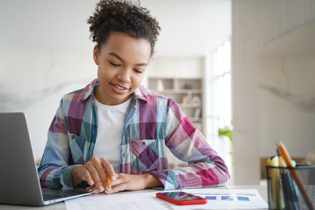 Przystojna uczennica afro uczy się zdalnie w domu i odrabia pracę domową Egzamin online